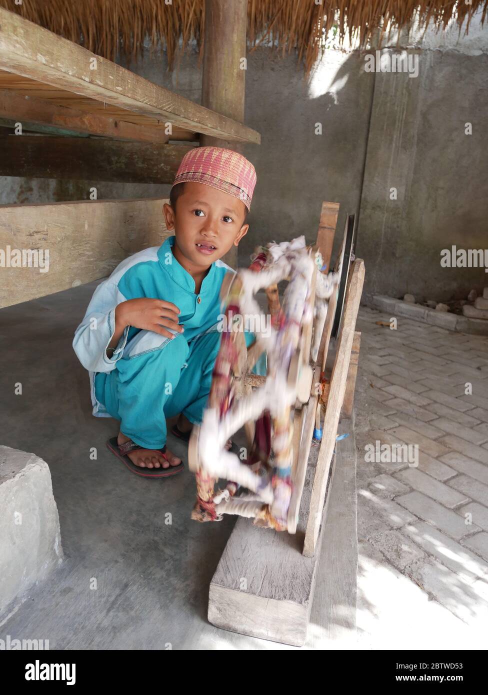 29 luglio 2018 - Lombok, Indonesia : UN ragazzo che gioca a ruota per filare il filato Foto Stock
