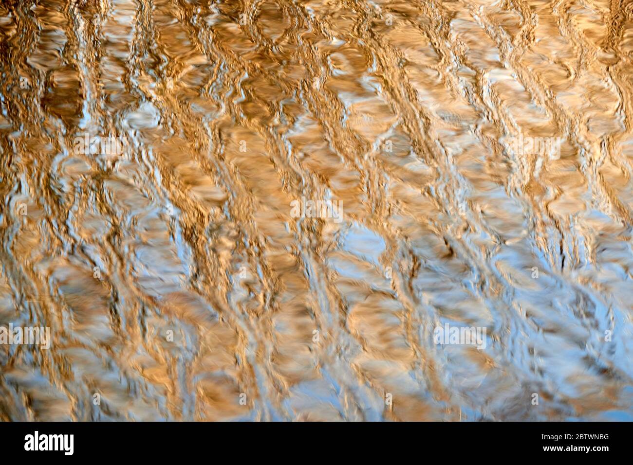 La superficie dell'acqua brilla l'oro, le piccole onde formano un bellissimo modello. Stoccarda, Germania Foto Stock