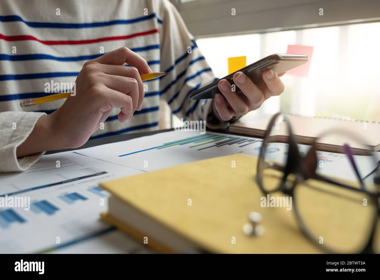 Primo piano di un contabile che tiene la matita lavorando sulla calcolatrice per calcolare il rapporto dei dati finanziari; Foto Stock