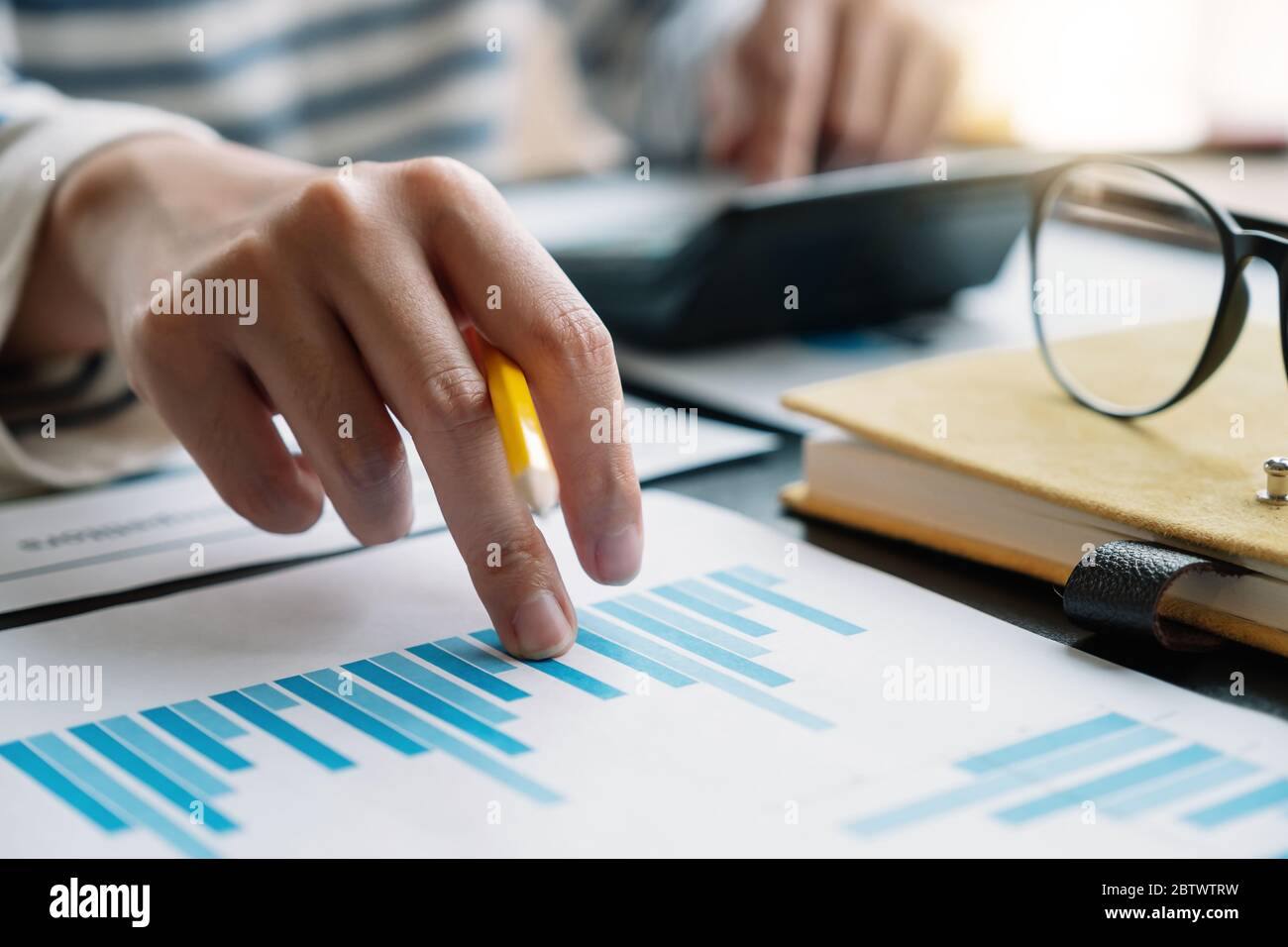 Donna d'affari che lavora in finanza e contabilità analizza il budget finanziario con la calcolatrice in ufficio Foto Stock