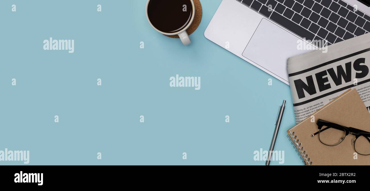 Creativo piatto di forniture per ufficio mockup con notebook, tazza da caffè caldo, bicchieri, libri e accessori isolati su fondo blu lungo banner, Top Foto Stock