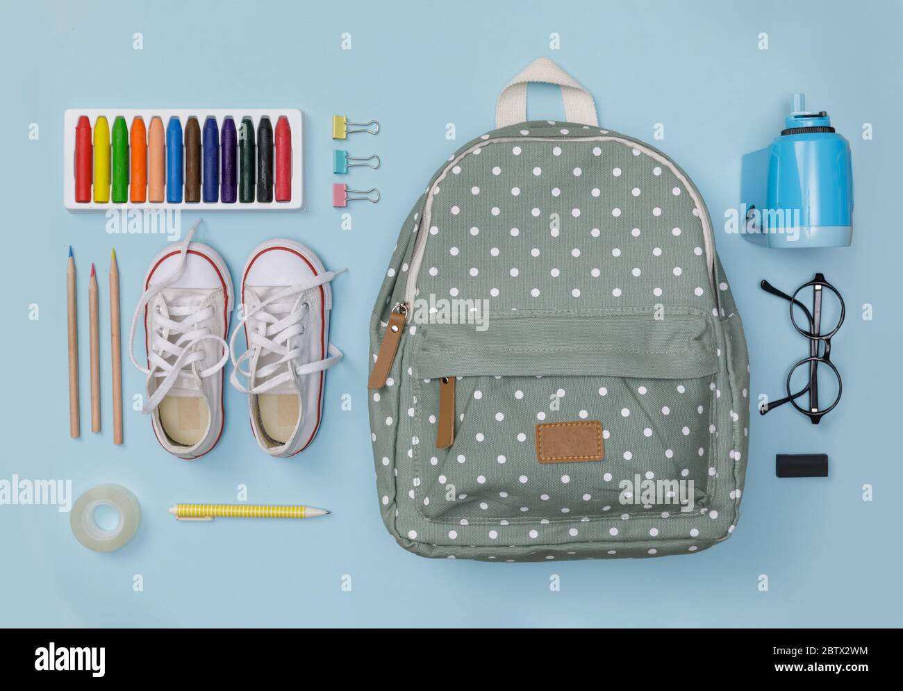 Piatto creativo di educazione blu tavolo con zaino, scarpe, pastello colorato, occhiali, isolato su sfondo blu, concetto di educazione e bac Foto Stock