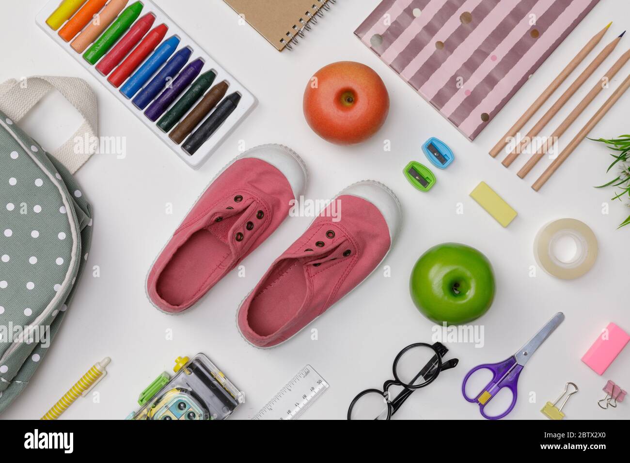 Piatto creativo di istruzione tavola bianca con zaino, libri per studenti, scarpe, pastello colorato, occhiali, isolato su sfondo bianco, concetto di Foto Stock
