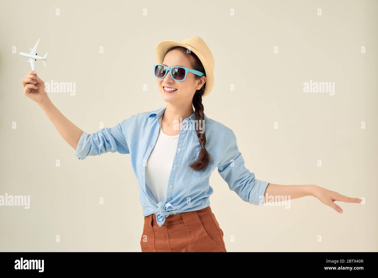 Closeup ritratto di bella donna in cappello di paglia tenendo in mano il modello di aeroplano, sognando di vacanze Foto Stock