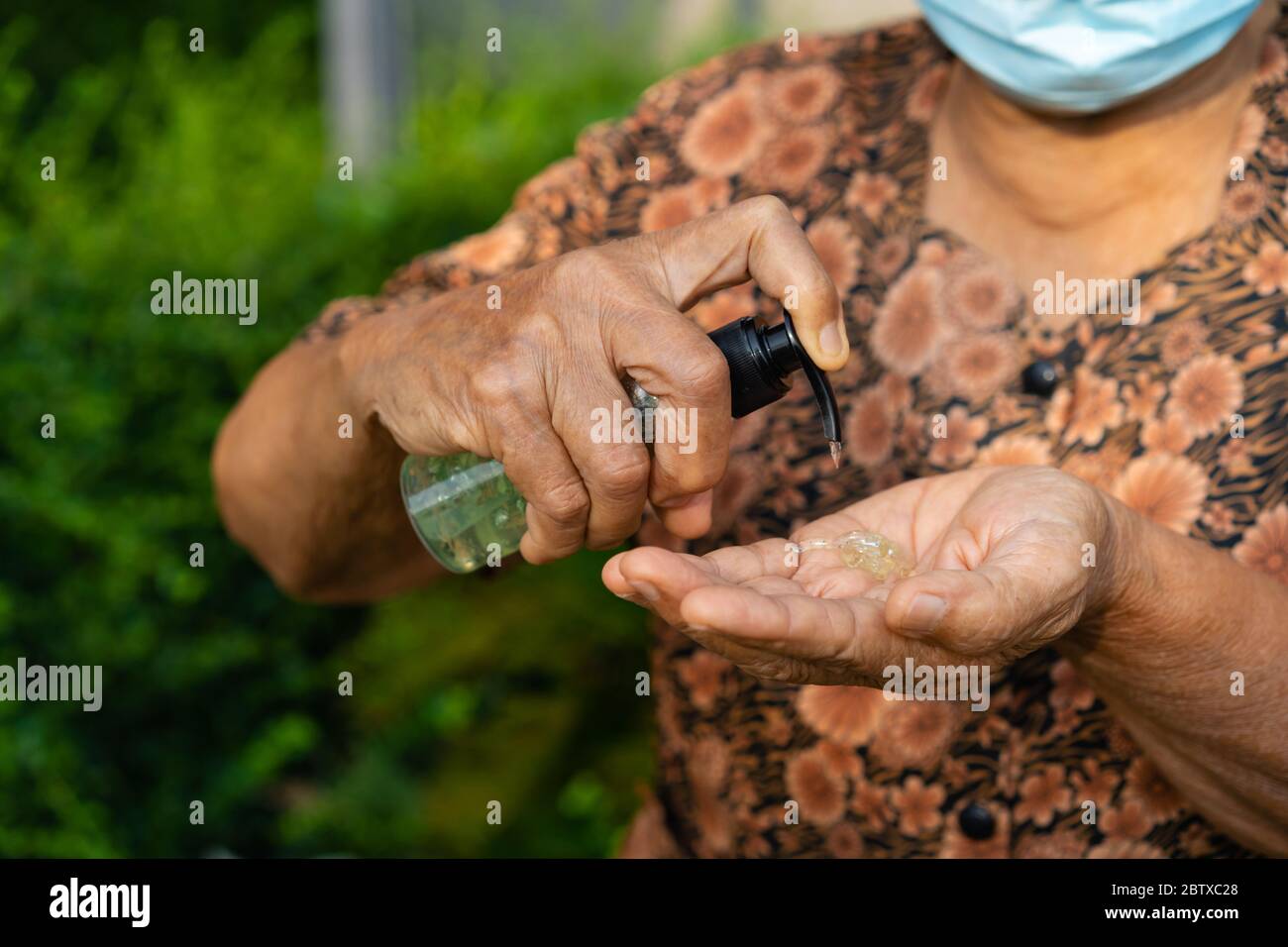 donna anziana che usa gel di alcol per lavare la mano, protezione del coronavirus Foto Stock