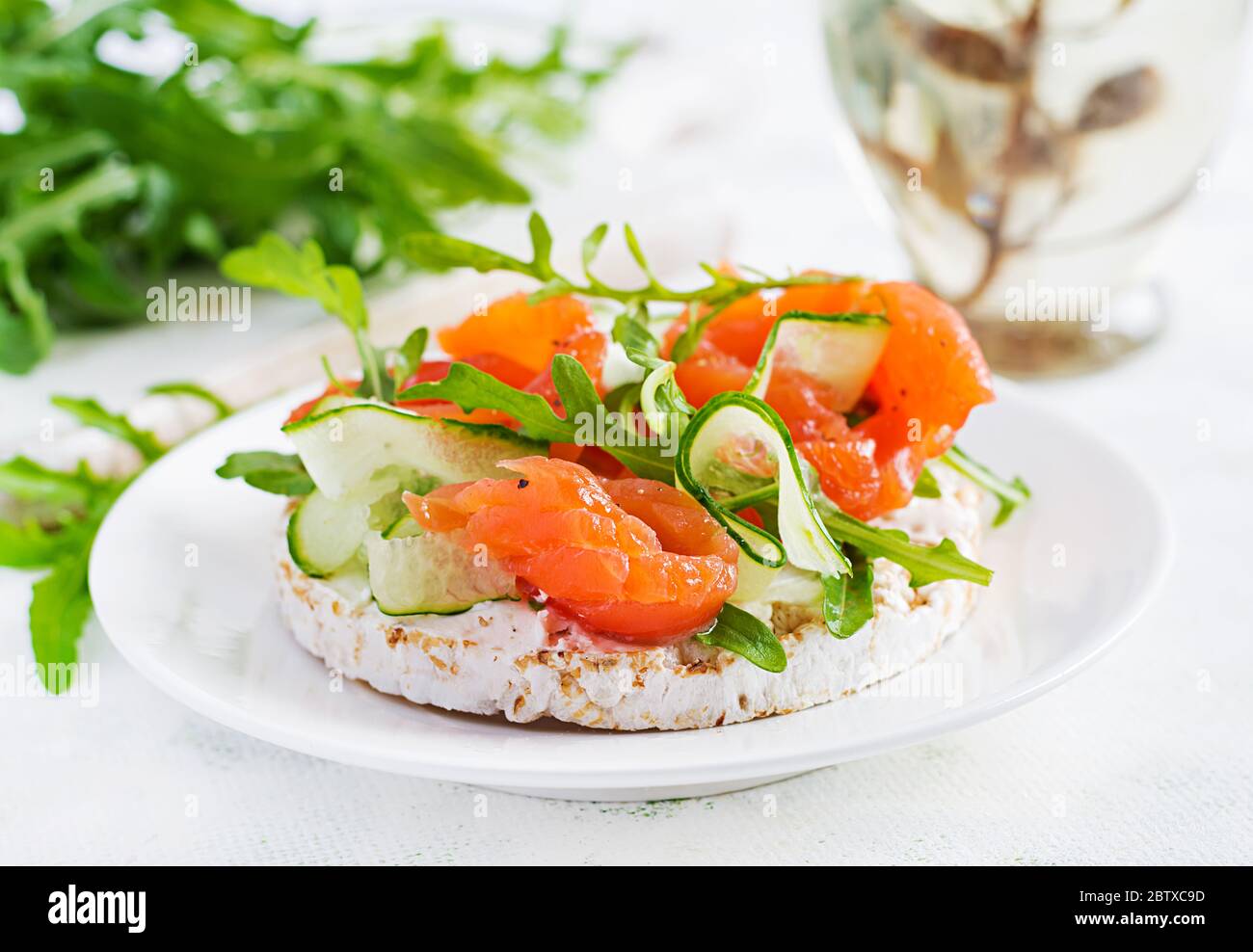 Sandwich aperto con salmone salato con croccante, formaggio spalmabile, cetriolo a fette e rucola sul piatto. Foto Stock