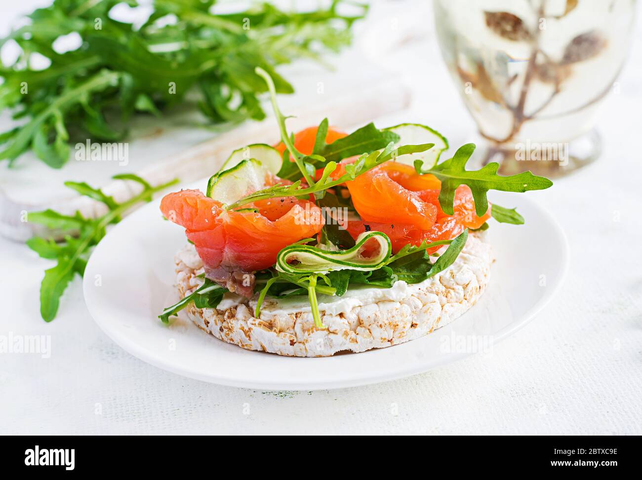 Sandwich aperto con salmone salato con croccante, formaggio spalmabile, cetriolo a fette e rucola sul piatto. Foto Stock