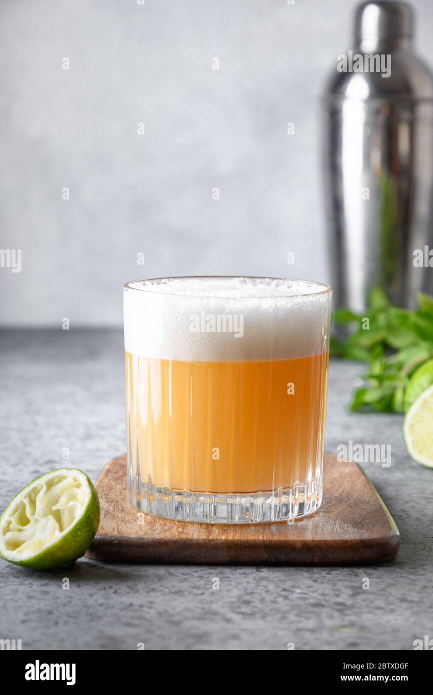 Cocktail Pisco Sour. Wiskey con calce, albume d'uovo, sciroppo di zucchero in vetro su tavola di pietra grigia. Shot verticale Foto Stock