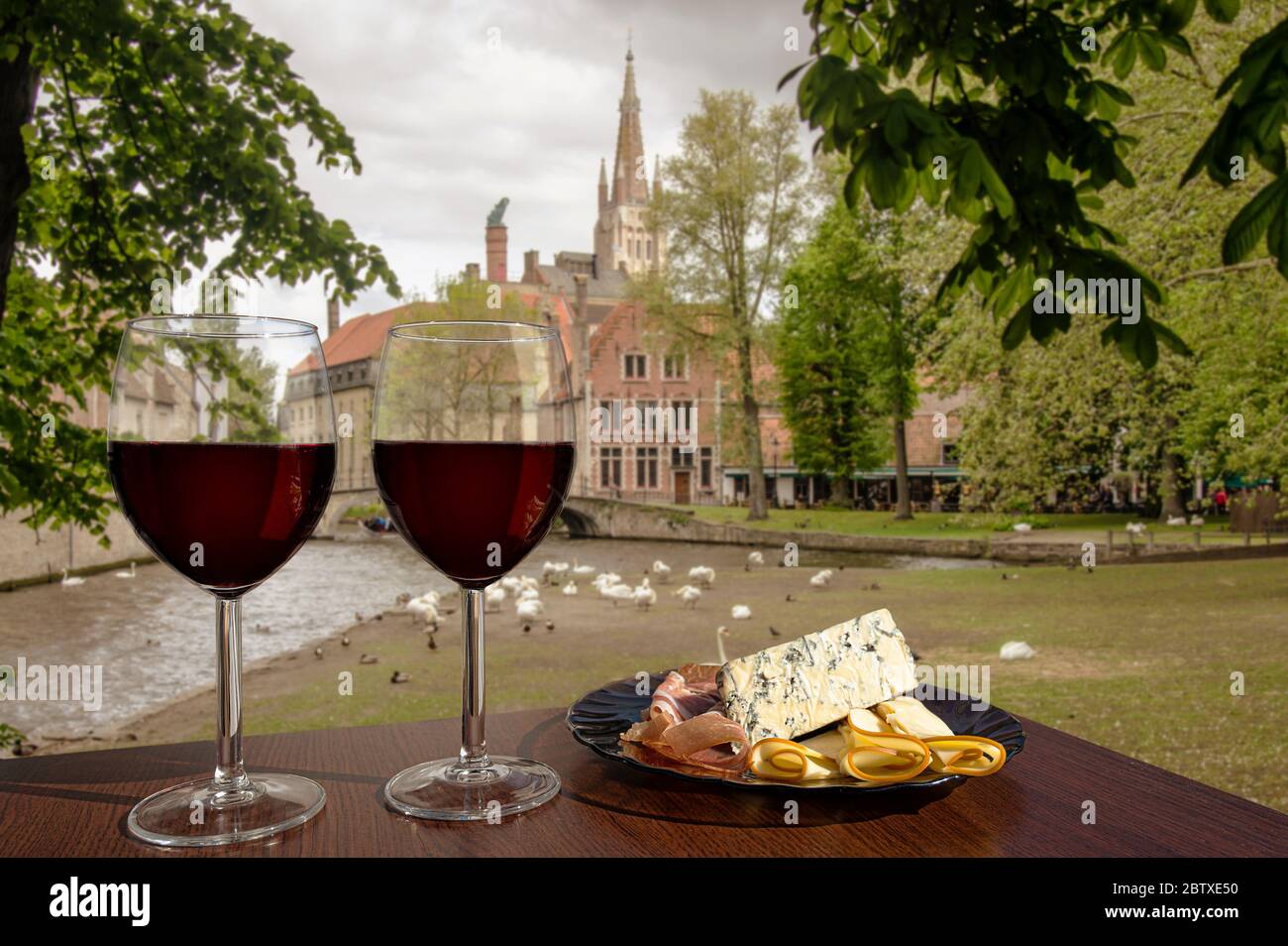 Due bicchieri di vino con assortimento di salumi sulla vista di Bruges, Belgio. Bicchiere di vino rosso con diversi spuntini - piatto con prosciutto, a fette Foto Stock