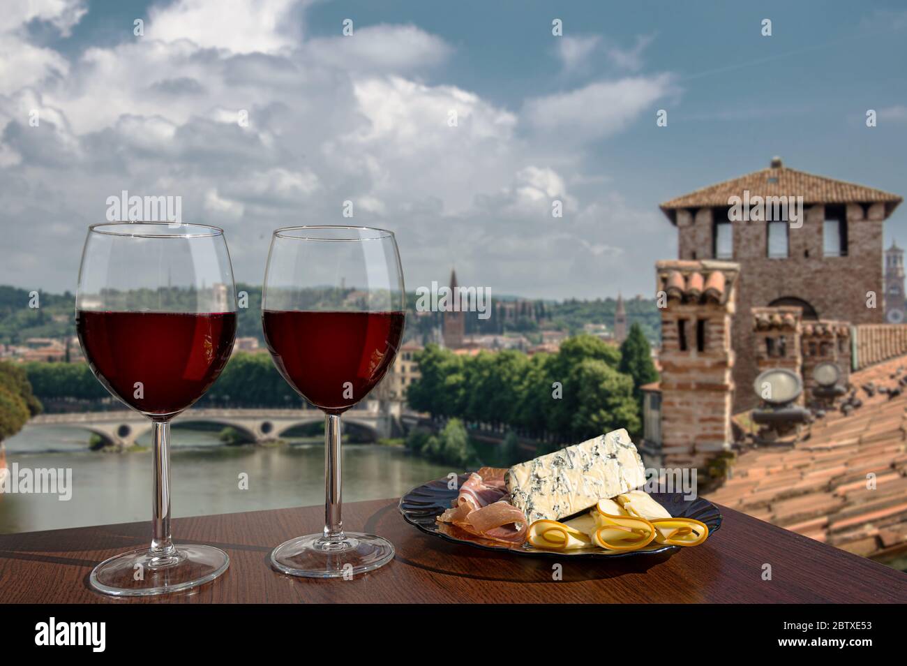 Due bicchieri di vino con assortimento di salumi con vista su Verona. Bicchiere di vino rosso con diversi spuntini - piatto con prosciutto, a fette, chee blu Foto Stock
