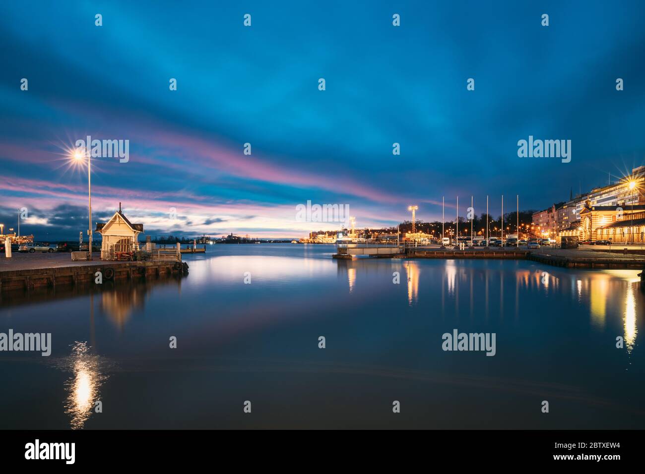Helsinki, Finlandia. Paesaggio con il molo della città, Jetty al tramonto all'alba. Blue Sky si riflette nella tranquilla superficie dell'acqua di mare. Ormeggio in illuminazione Foto Stock