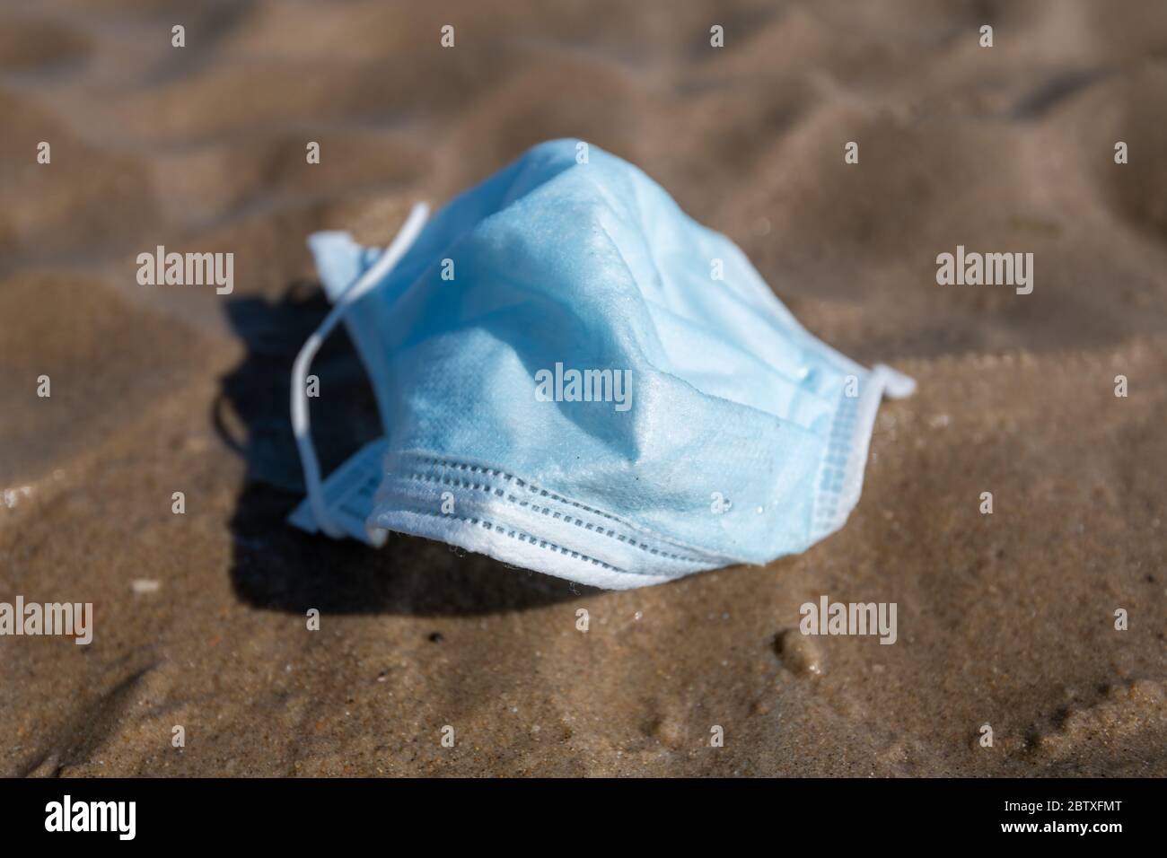 Maschera chirurgica abbandonata su una spiaggia Foto Stock