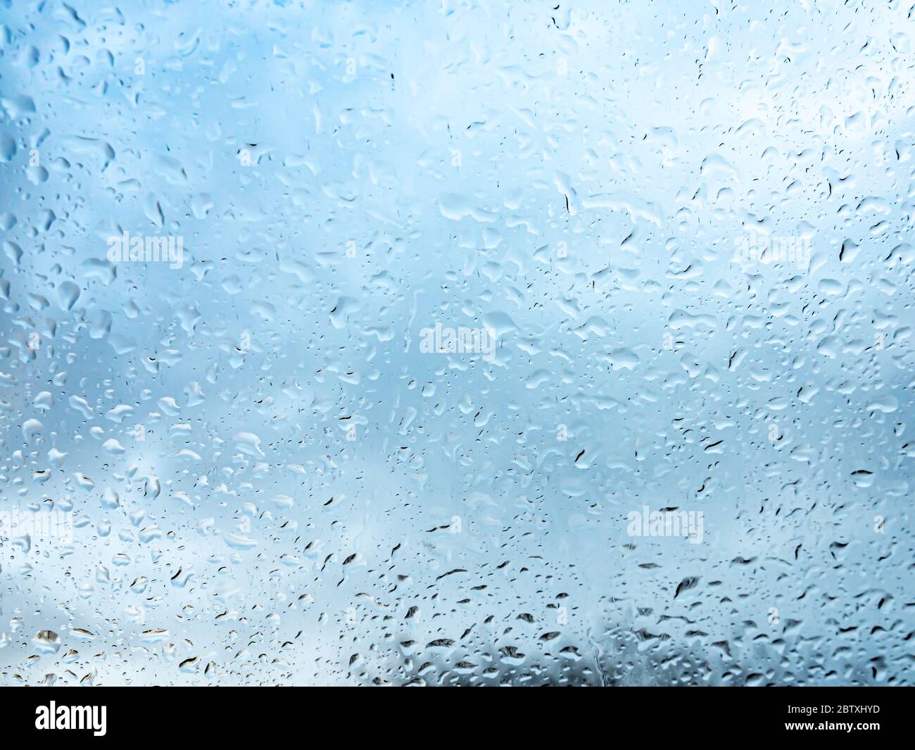 Finestra bagnata con gocce di pioggia e un cielo nuvoloso su sfondo. Foto Stock
