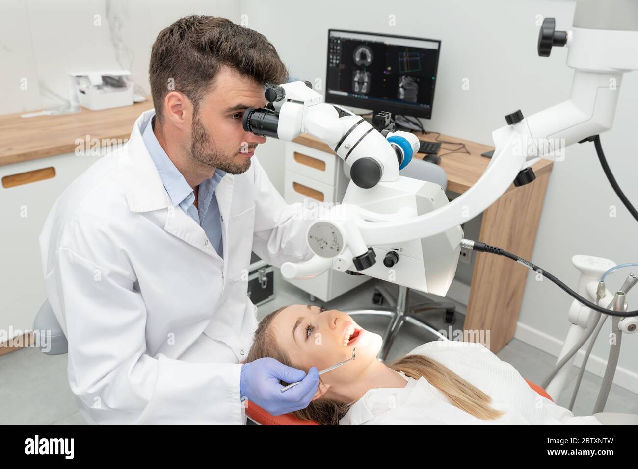 Dentista che controlla i denti del paziente presso l'ufficio di clinica odontoiatrica. Microscopio, trattamento dentistico professionale Foto Stock