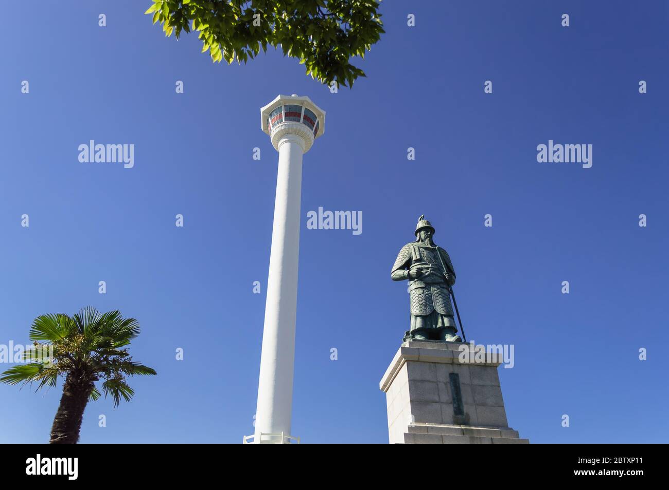 Busan, Corea del Sud, 14 settembre 2019: Vista della torre Busan con la statua di Yi Sun-sin di fronte ad essa e cieli blu con alberi sullo sfondo Foto Stock