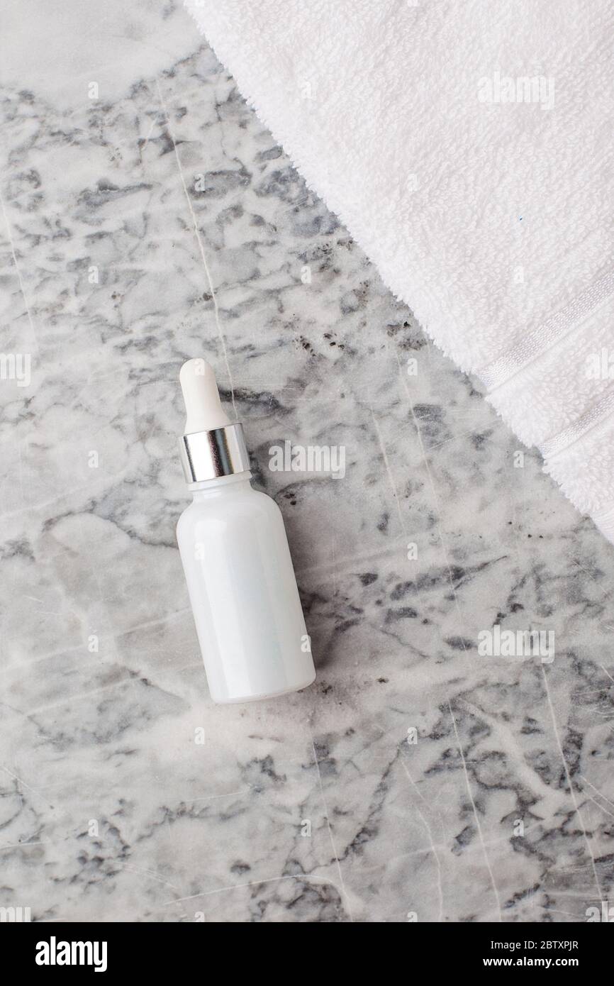Prodotto cosmetico naturale per la cura della pelle. Contagocce in vetro bianco su fondo in marmo. Siero o olio essenziale con estratto di erbe. Marchio Foto Stock