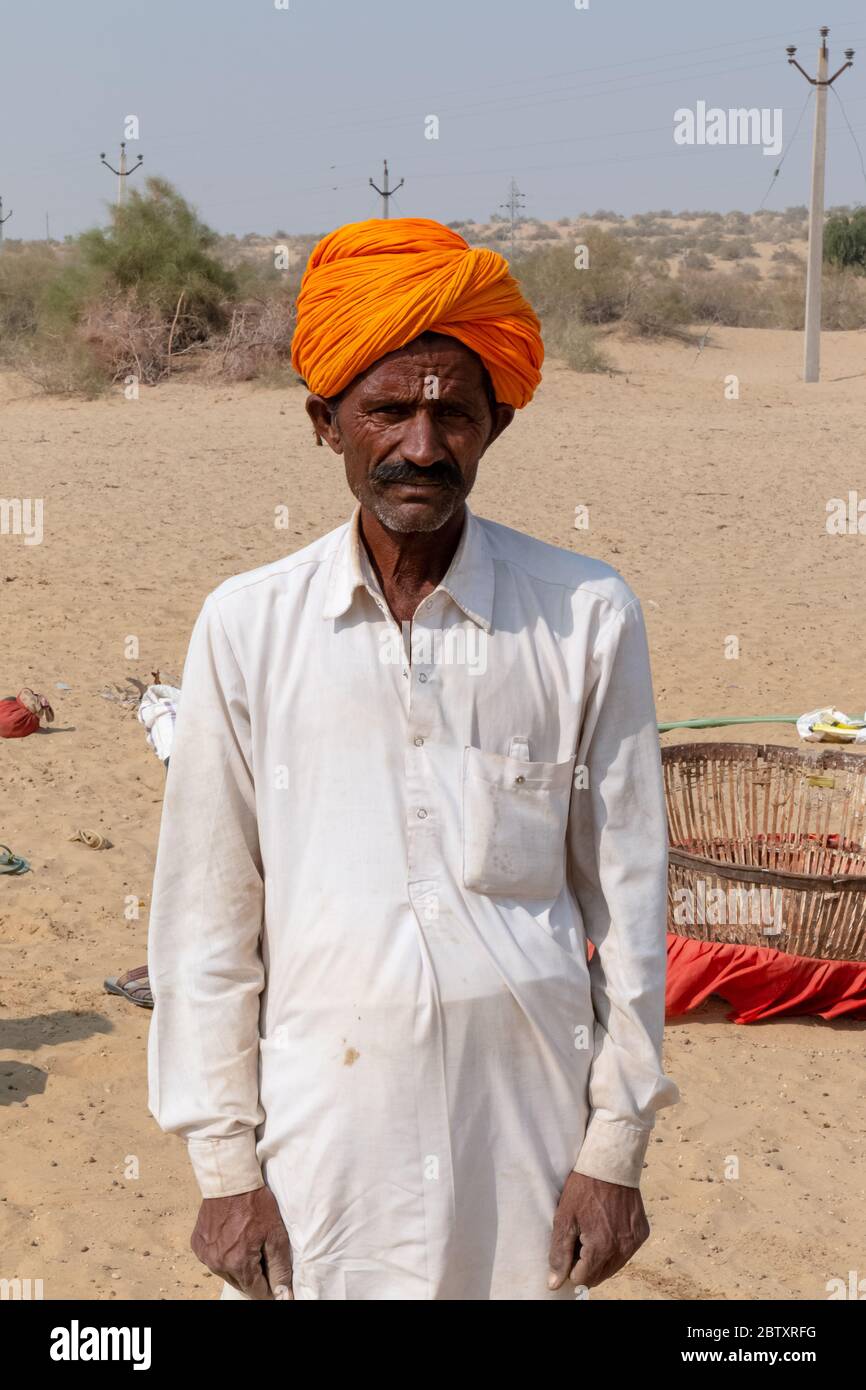 Ritratto di un uomo da Jaisalmer in piedi nel deserto del Thar con turban colorato, Jaisalmer, Rajasthan Foto Stock
