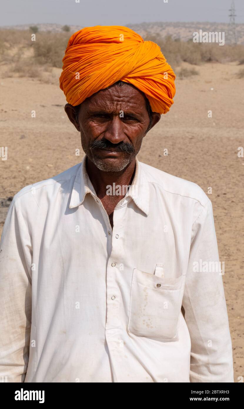 Ritratto di un uomo da Jaisalmer in piedi nel deserto del Thar con turban colorato, Jaisalmer, Rajasthan Foto Stock