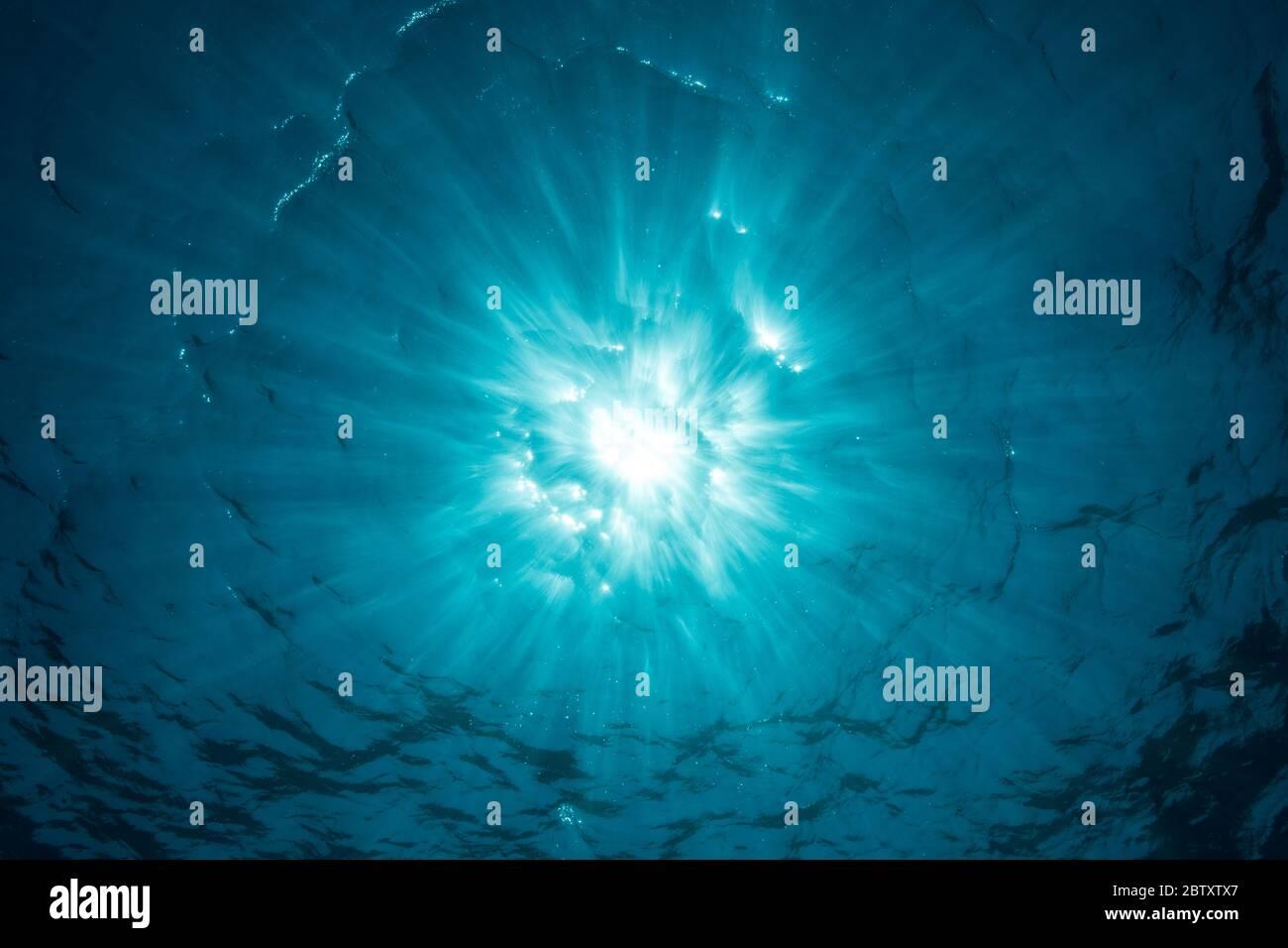 Un'esplosione di sole appena sotto la superficie dell'oceano, con la luce del sole che scende, Nusa Penida, Bali, Indonesia. Foto Stock