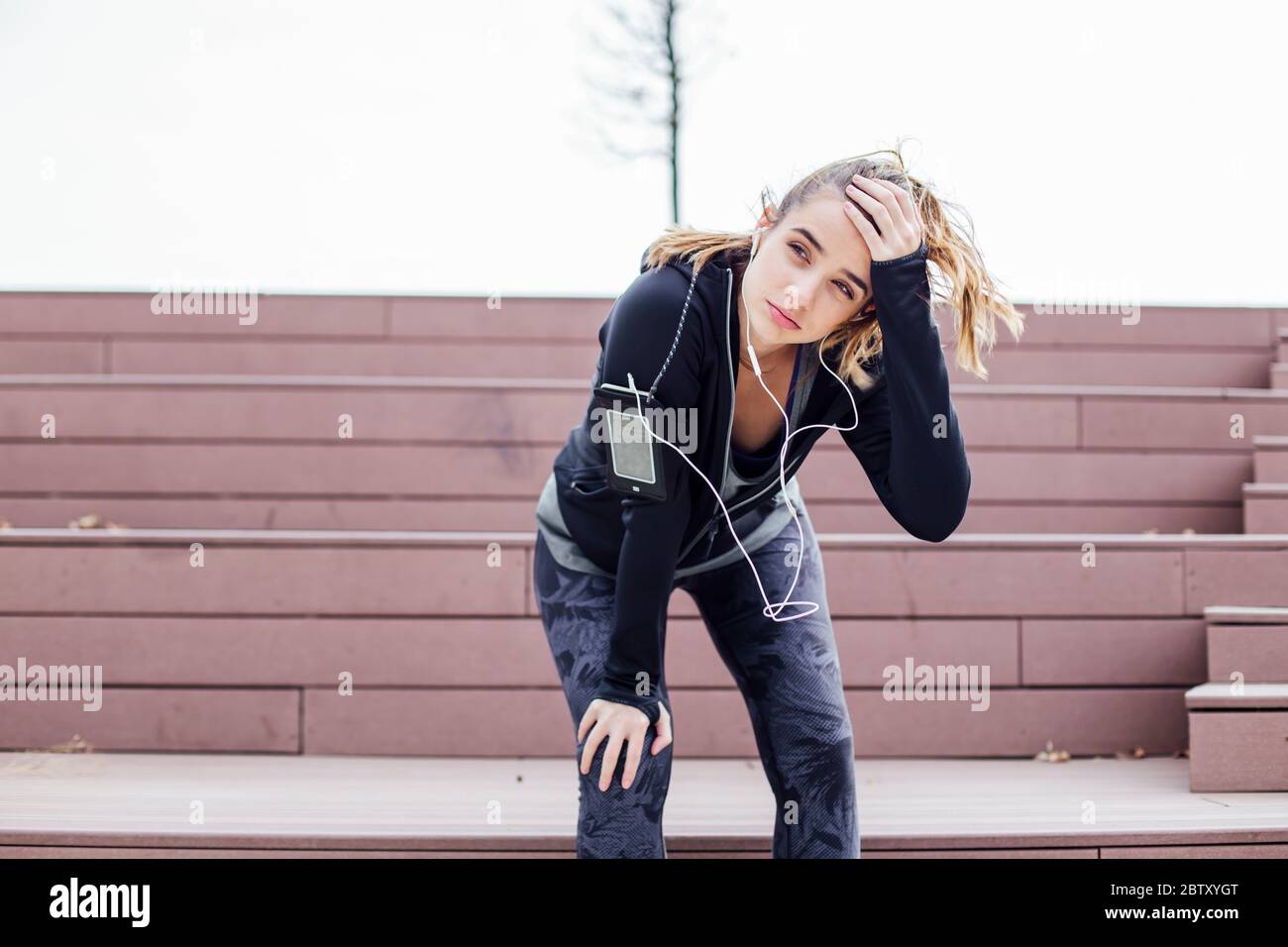 Stanca giovane donna che riposa dopo aver fatto jogging all'aperto Foto Stock