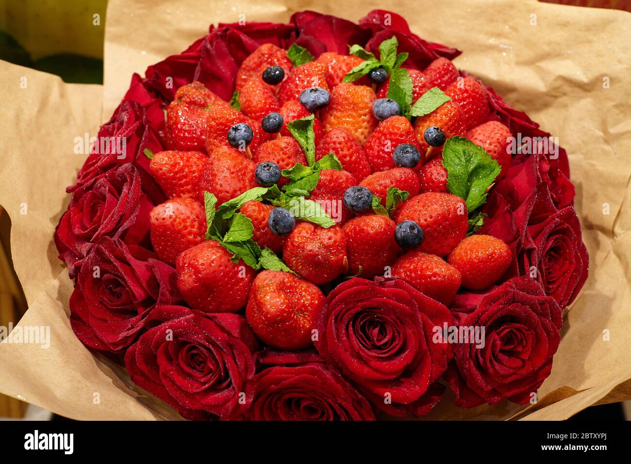 Delizioso bouquet di fragole, rose, mirtilli e foglie di menta. Primo piano Foto Stock