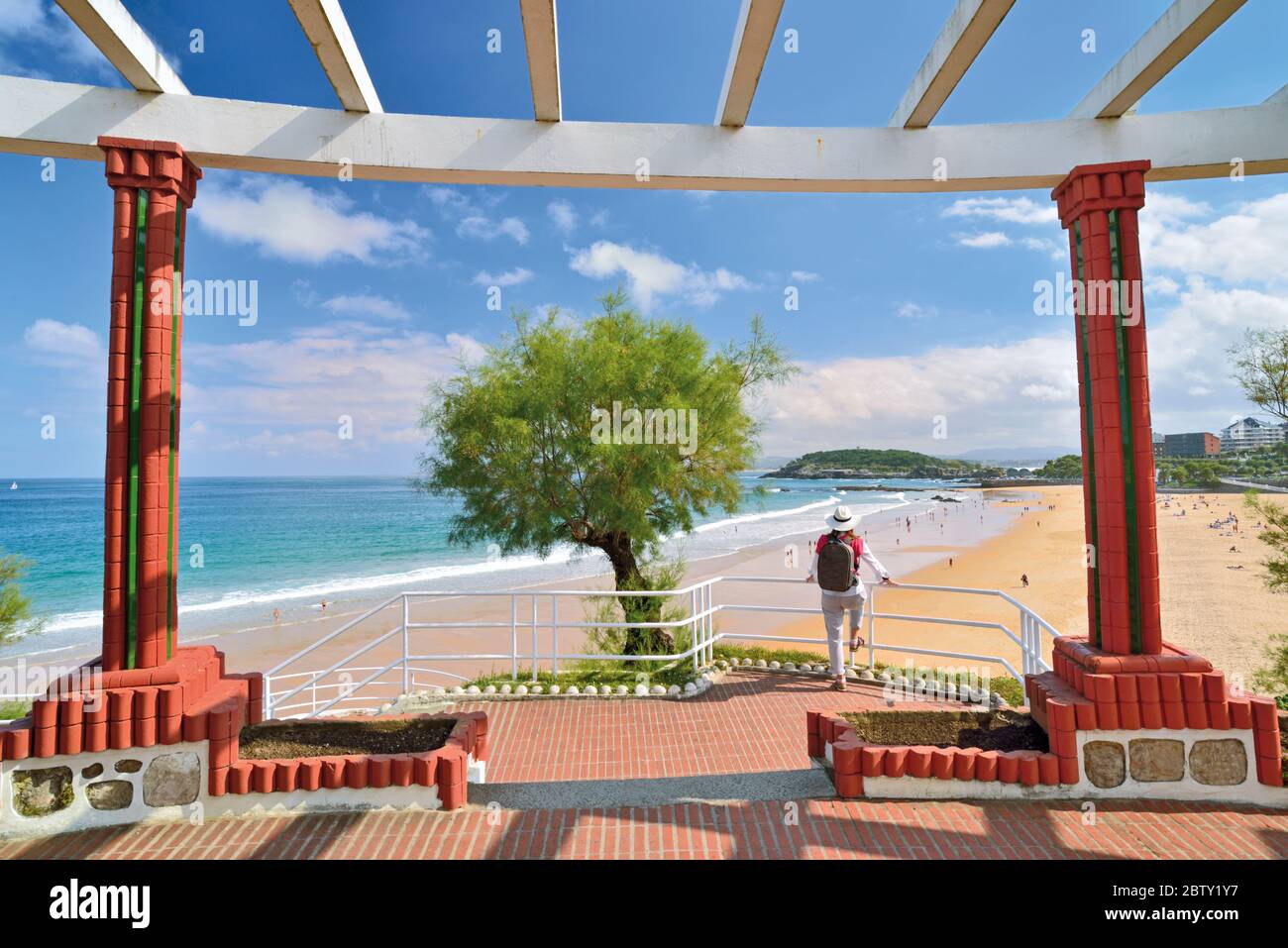 Donna con zaino che si affaccia sulla spiaggia urbana da un punto di vista della città ben curato Foto Stock