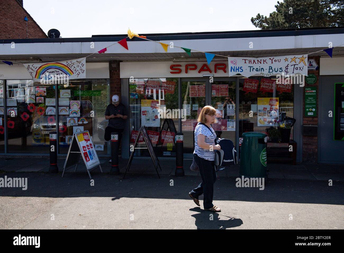 Wollaston High Street, dove l'artista Luke Perry ha appeso il bunging, con messaggi di sostegno per i vicini e i lavoratori chiave, per creare un corridoio di 500 metri di colore attraverso il villaggio delle West Midlands. Perry ha chiesto ai residenti e ai negozianti locali di presentare disegni e messaggi, che poi dipinse a mano e cucì su conchettando con l'aiuto di volontari. Foto Stock