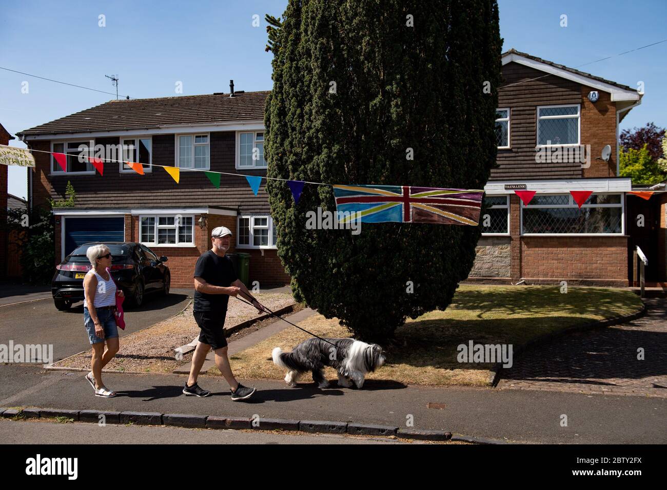 Duncombe Street a Wollaston, dove l'artista Luke Perry ha appeso bunting con messaggi di sostegno per i vicini e i lavoratori chiave, per creare un corridoio di 500 metri di colore attraverso il villaggio delle West Midlands. Perry ha chiesto ai residenti e ai negozianti locali di presentare disegni e messaggi, che poi dipinse a mano e cucì su conchettando con l'aiuto di volontari. Foto Stock