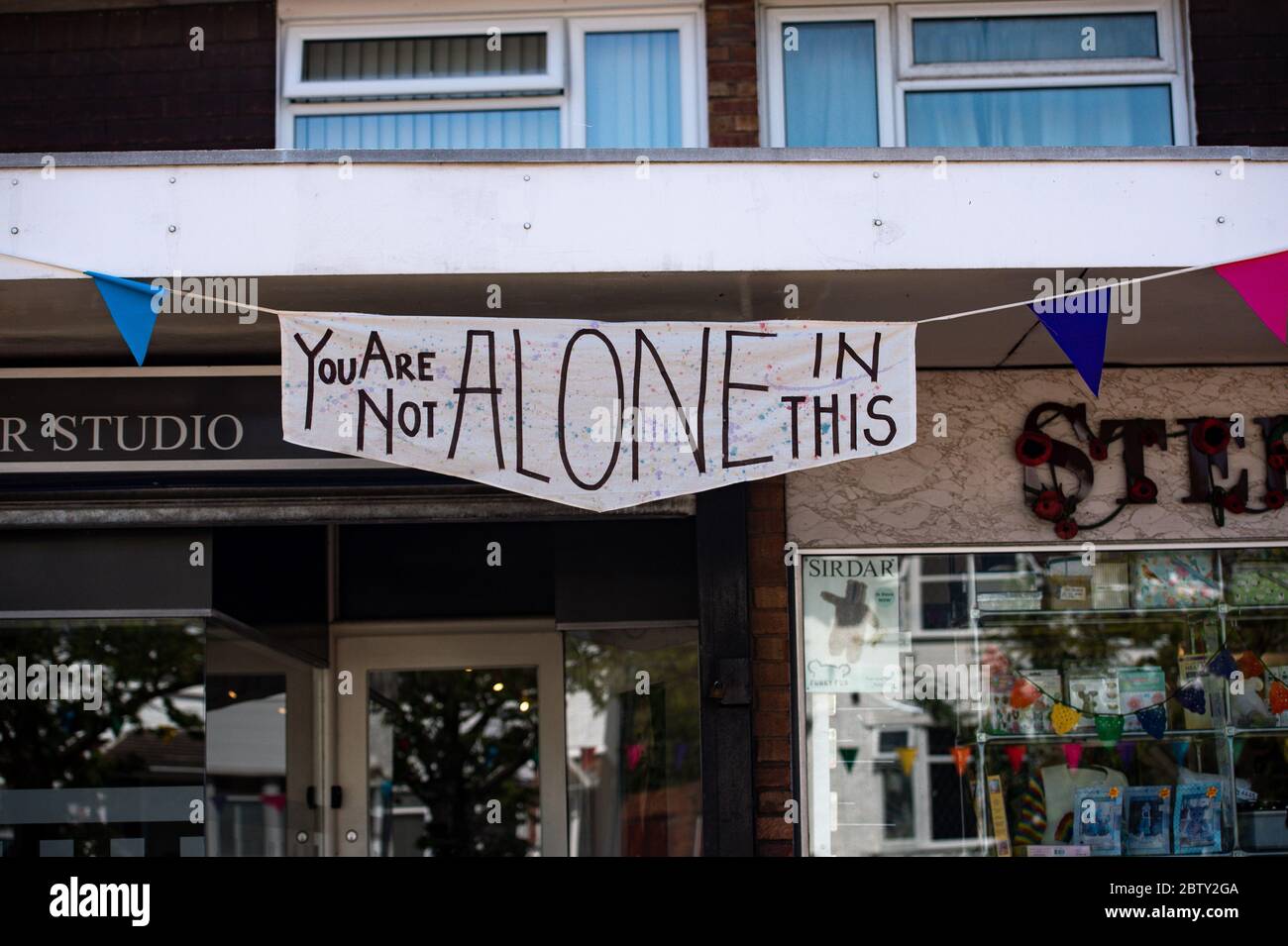Wollaston High Street, dove l'artista Luke Perry ha appeso il bunging, con messaggi di sostegno per i vicini e i lavoratori chiave, per creare un corridoio di 500 metri di colore attraverso il villaggio delle West Midlands. Perry ha chiesto ai residenti e ai negozianti locali di presentare disegni e messaggi, che poi dipinse a mano e cucì su conchettando con l'aiuto di volontari. Foto Stock