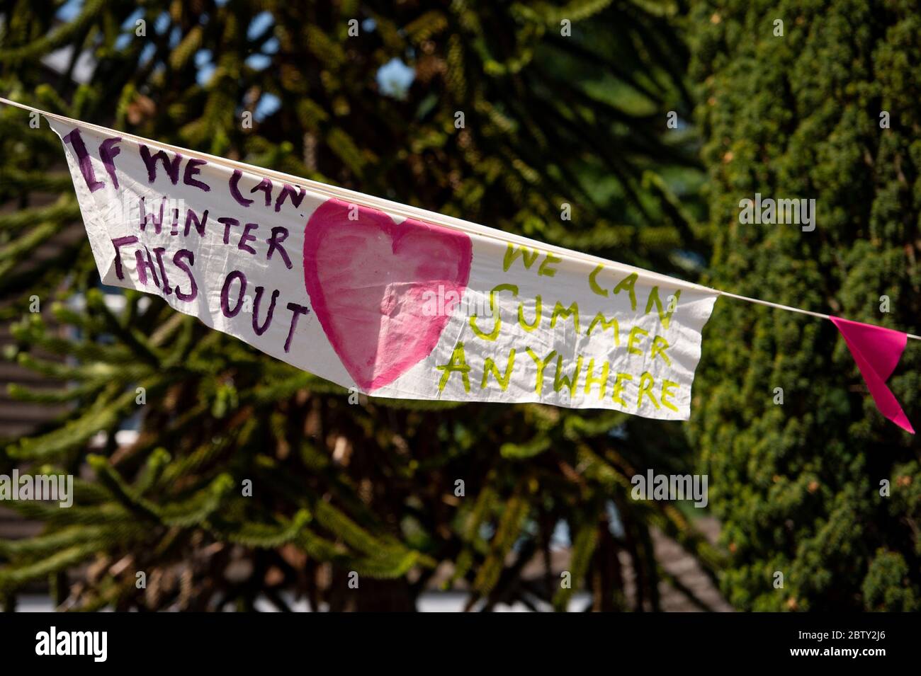 Duncombe Street a Wollaston, dove l'artista Luke Perry ha appeso bunting con messaggi di sostegno per i vicini e i lavoratori chiave, per creare un corridoio di 500 metri di colore attraverso il villaggio delle West Midlands. Perry ha chiesto ai residenti e ai negozianti locali di presentare disegni e messaggi, che poi dipinse a mano e cucì su conchettando con l'aiuto di volontari. Foto Stock