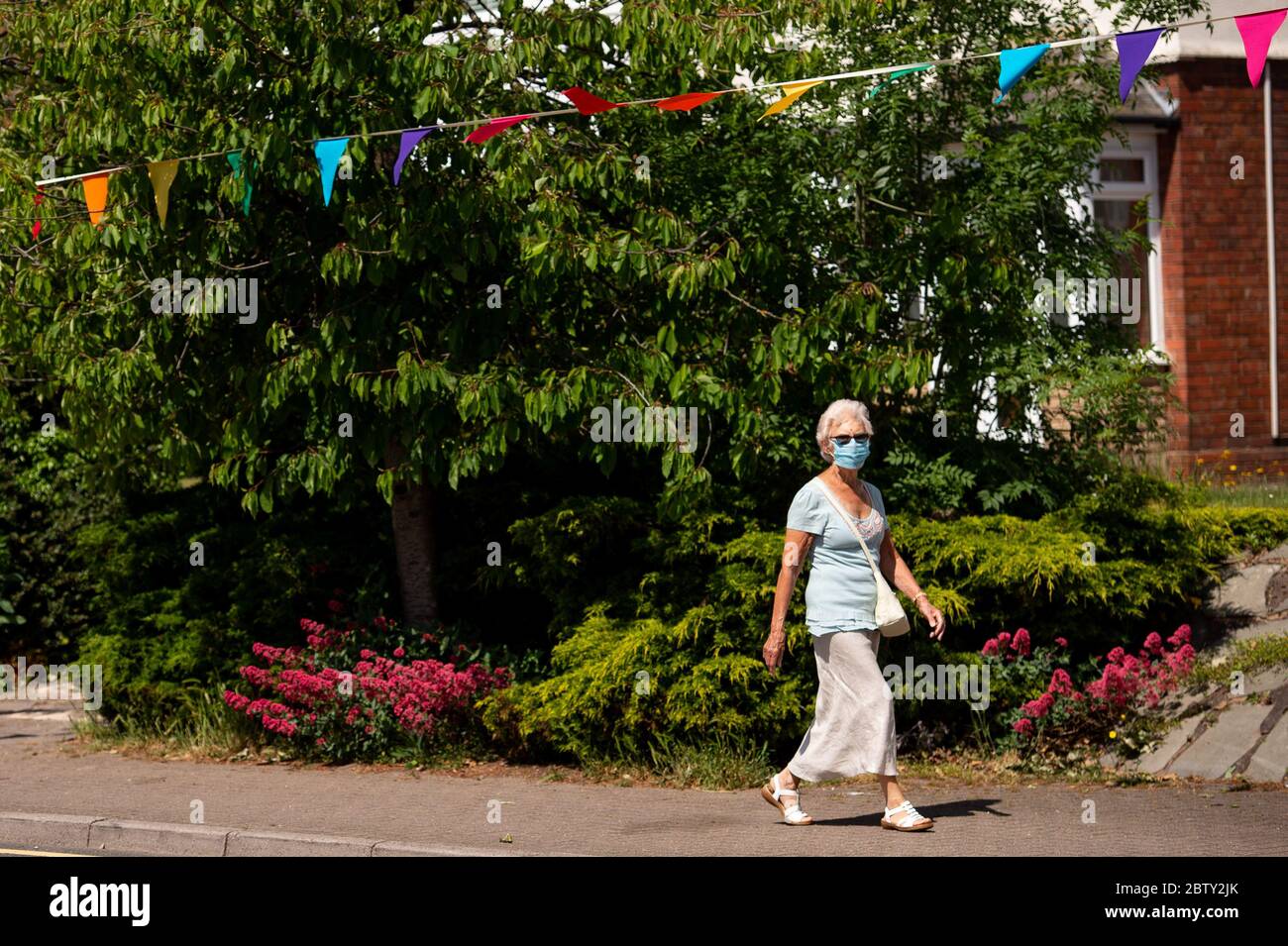 Wollaston High Street, dove l'artista Luke Perry ha appeso il bunging, con messaggi di sostegno per i vicini e i lavoratori chiave, per creare un corridoio di 500 metri di colore attraverso il villaggio delle West Midlands. Perry ha chiesto ai residenti e ai negozianti locali di presentare disegni e messaggi, che poi dipinse a mano e cucì su conchettando con l'aiuto di volontari. Foto Stock