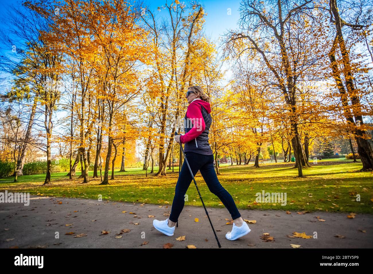 Nordic walking - medio-età della donna che lavora fuori nel parco della città Foto Stock