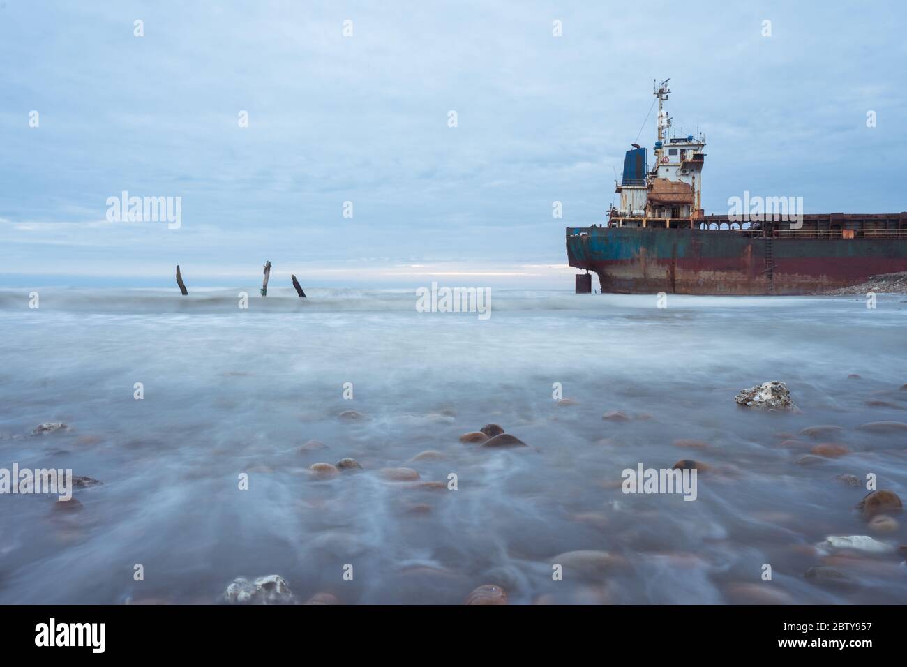 Hsinchu / Taiwan - 15 settembre 2019: Scatto lento paesaggio otturatore di barca arrugginita in costa rocciosa durante il tramonto Foto Stock