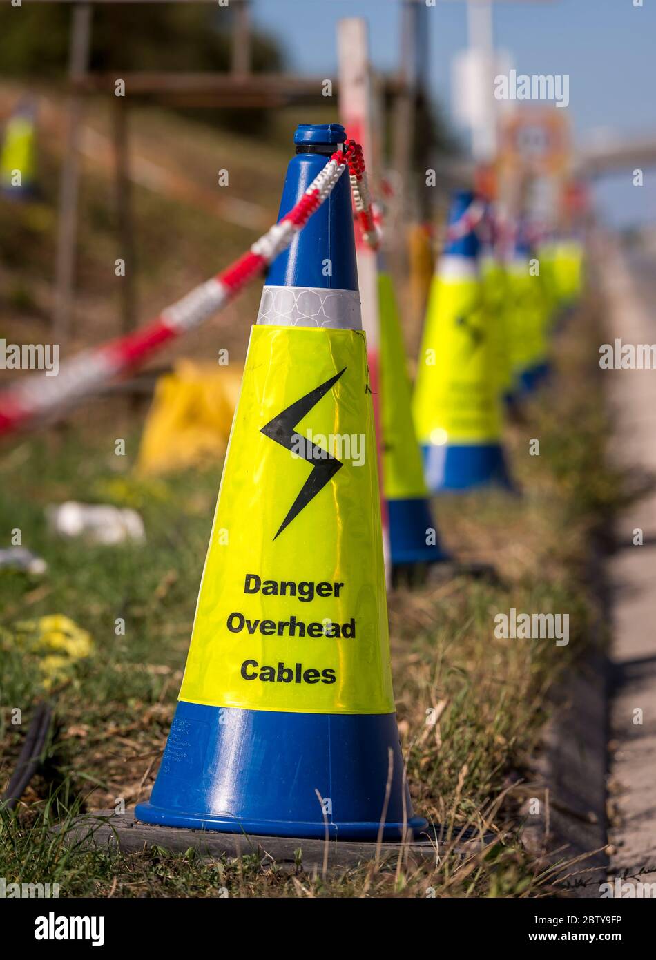 Coni blu che avvertono del pericolo di cavi di alimentazione sospesi in lavori stradali sull'autostrada M1 in Inghilterra. Foto Stock