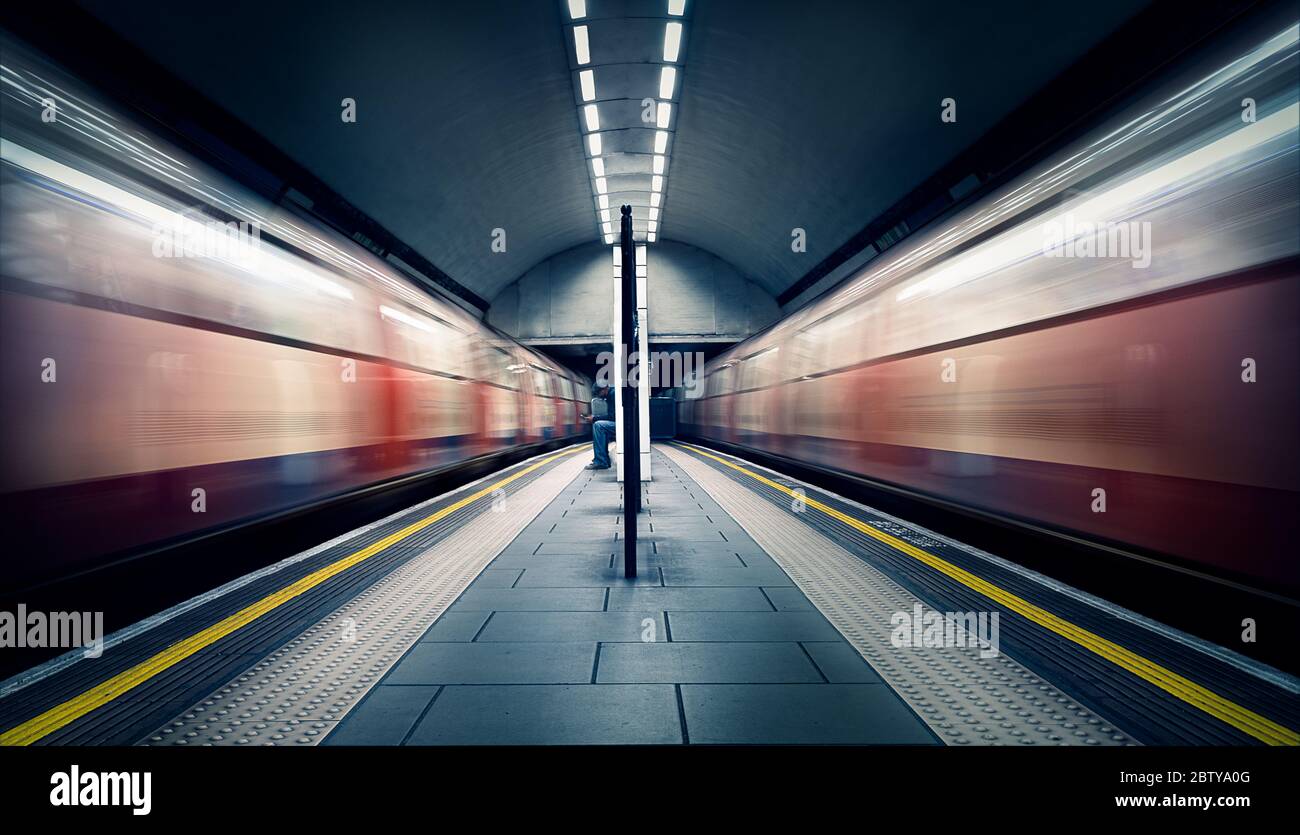 Due treni in movimento e un pendolarismo seduto alla stazione della metropolitana di Londra, Clapham Common, Clapham, Londra, Inghilterra, Regno Unito, Europa Foto Stock