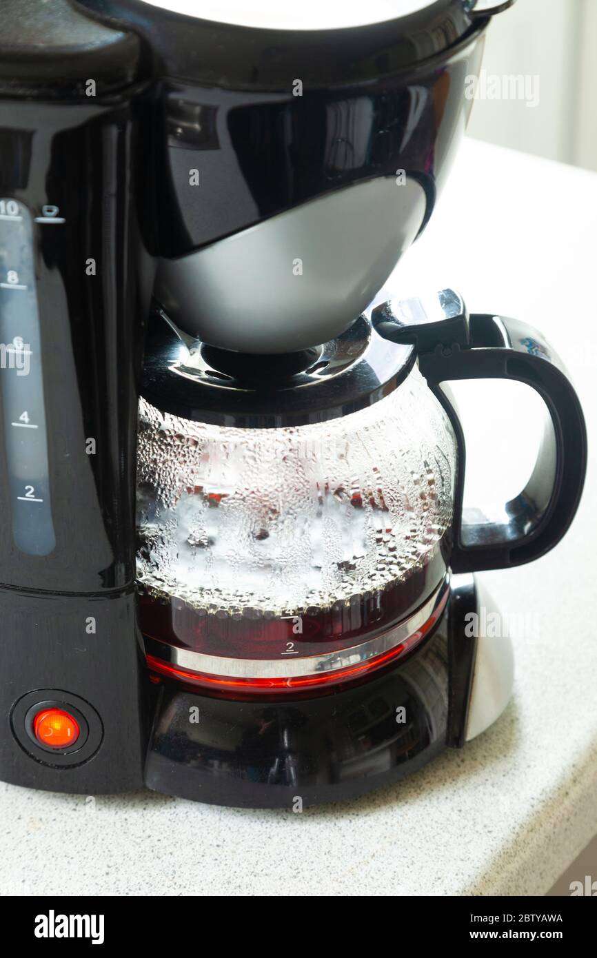 Primo piano di una macchina per il caffè in plastica per preparare una tazza di caffè fresca. Foto Stock