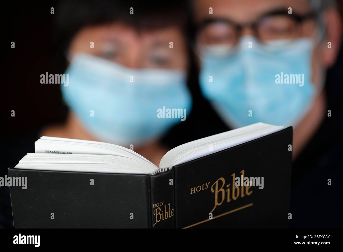 Uomo e donna che legge la bibbia con una maschera usa e getta per evitare il coronavirus contagioso (COVID-19), Francia, Europa Foto Stock