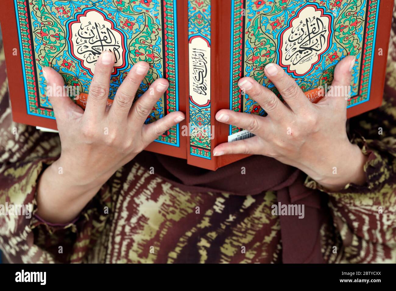 Donna musulmana che legge il Corano, la Moschea Nazionale (Masjid Negara), Kuala Lumpur, Malesia, Sud-Est asiatico, Asia Foto Stock