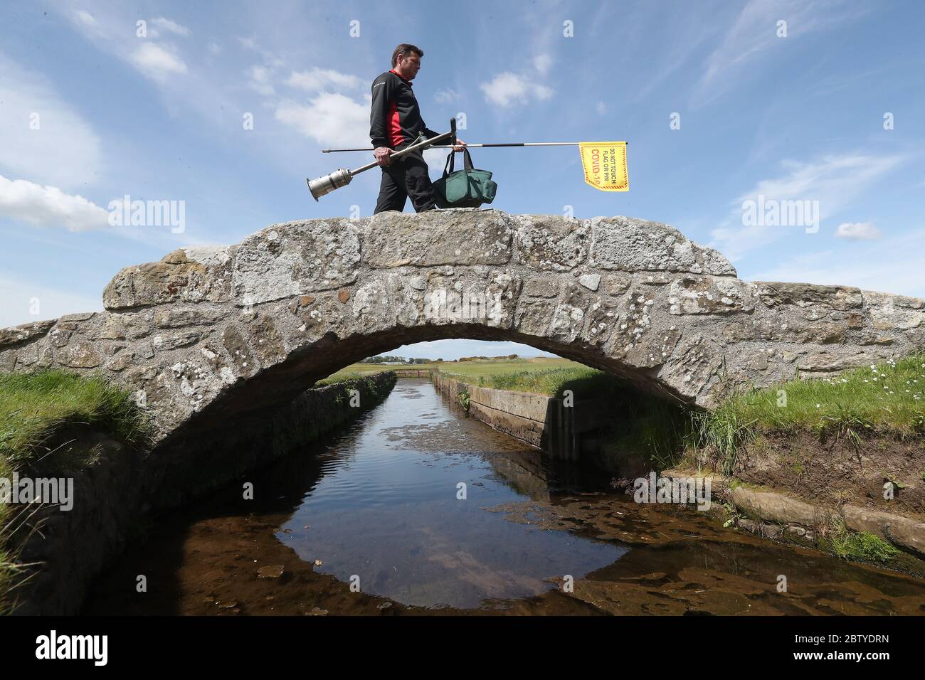 Il guardiano Simon Connah attraversa il ponte di Swilcan sul vecchio corso di St Andrews, a Fife, mentre i preparativi finali sono completati per il corso in vista della riapertura di domani. Il giorno in cui il primo ministro Nicola Sturgeon ha detto che la gente in Scozia potrà incontrare un'altra famiglia in un momento all'aperto da venerdì come misure di blocco per la pandemia di coronavirus facilità. Foto Stock