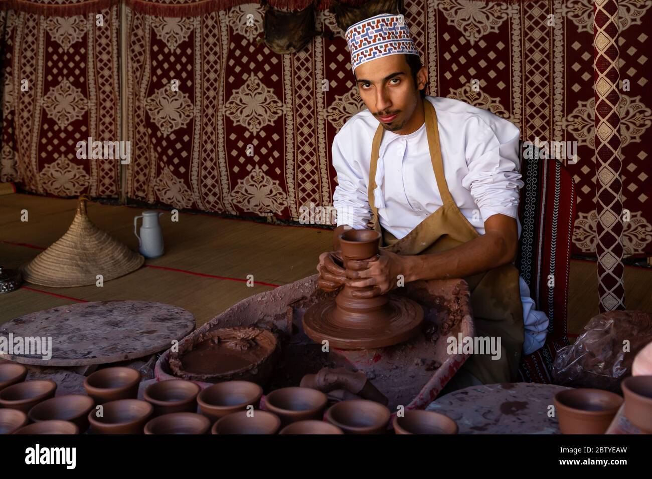 Omani potter lavorando sul suo giradischi, formando una ciotola di argilla con le mani nel forte di Nizwa, Oman Foto Stock