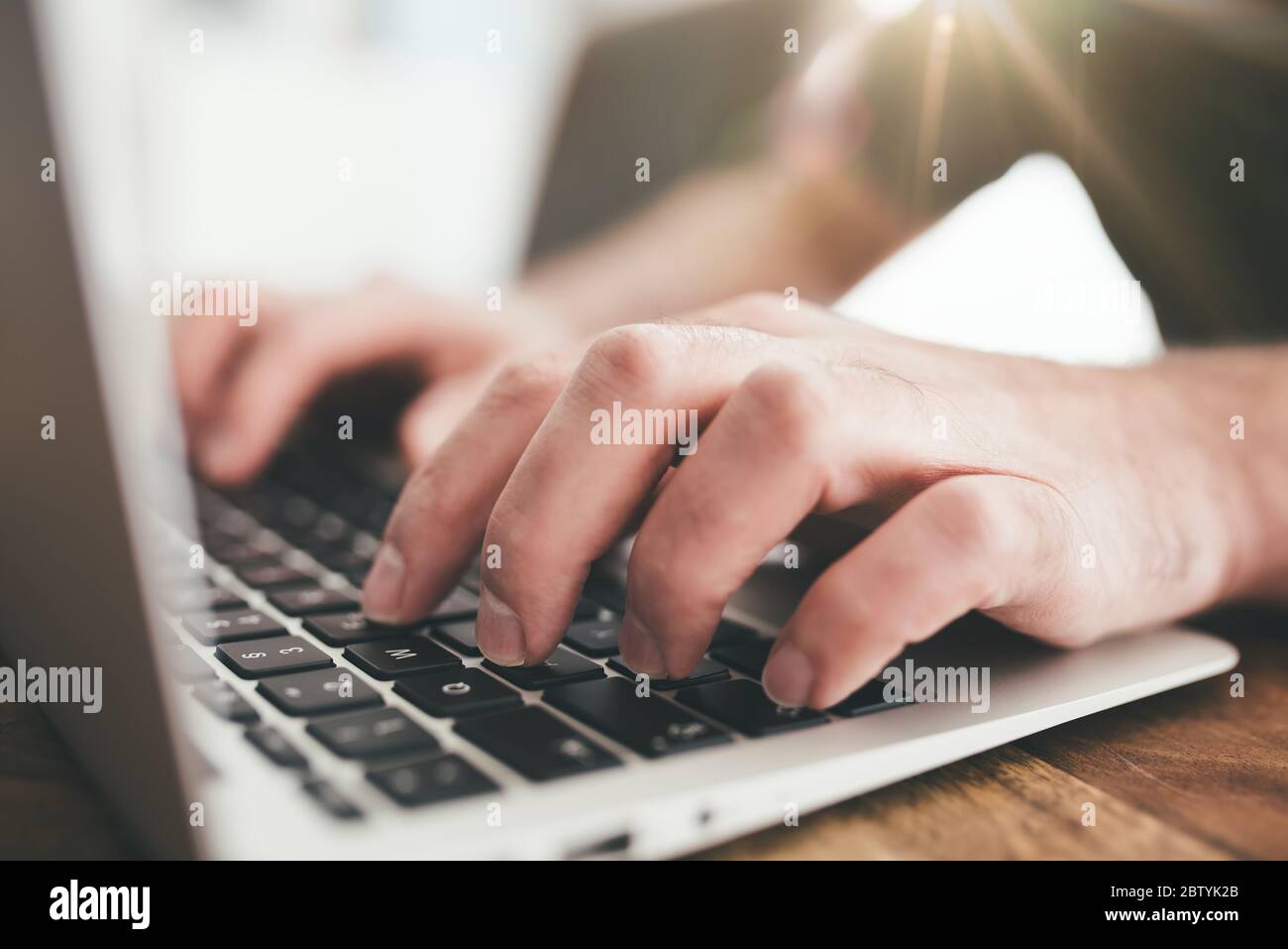 lavorando da casa concetto, primo piano di persona che scrive sul computer portatile su tavolo di legno Foto Stock