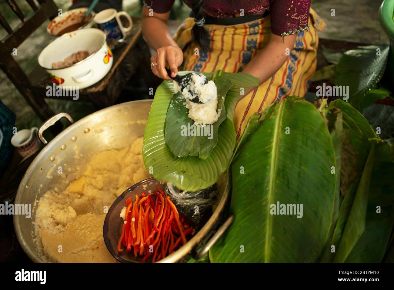 Tamales nella fabbricazione con buccia di mais e peperoncino, carne avvolta in foglie di banana poi cotto a vapore in una pentola grande. Natale giorno di tradizione Maya in Guatemala Foto Stock