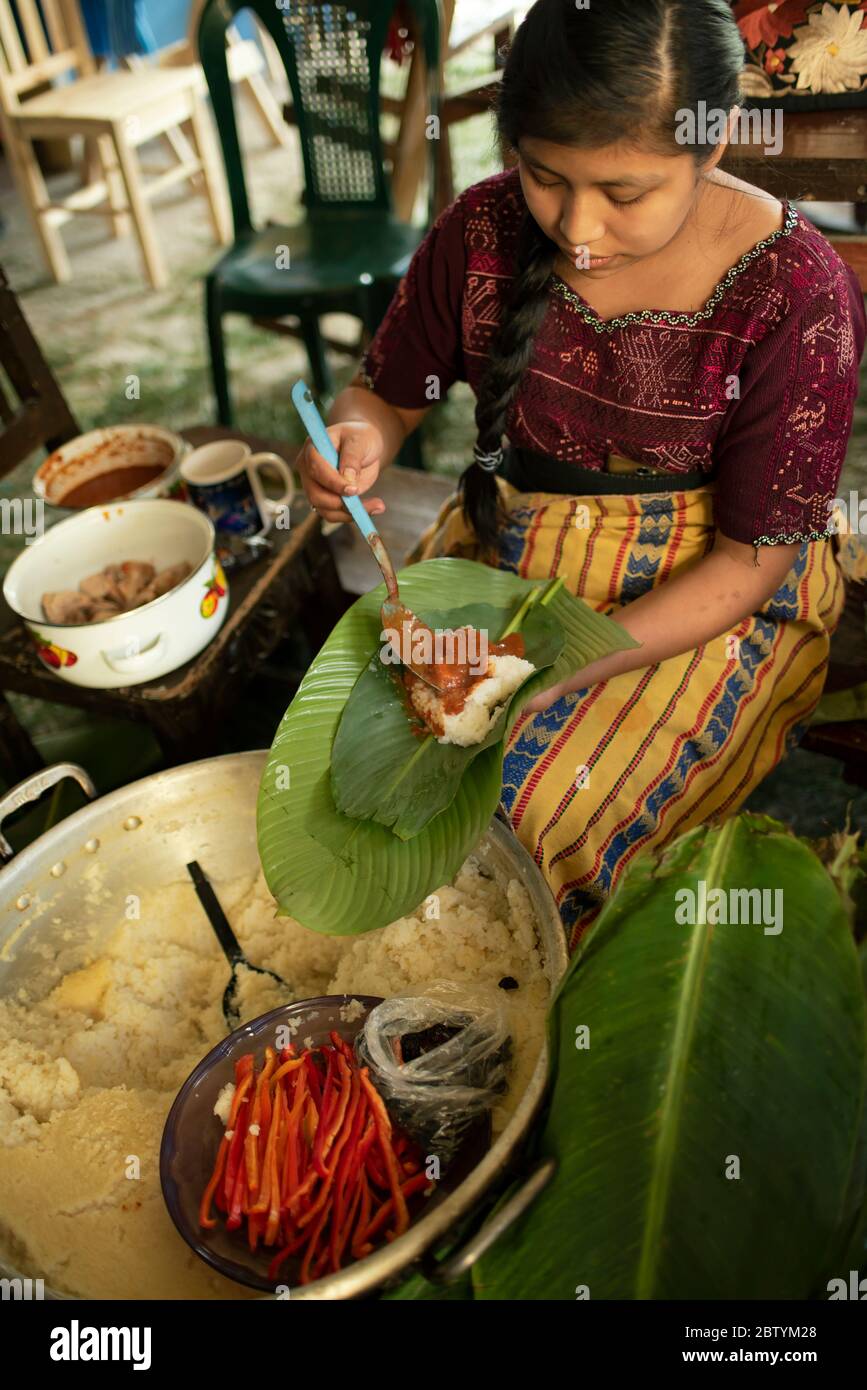 Maya ragazza che fa tamales con buccia di mais, peperoncino e carne avvolta in foglie di banana poi cucinato in un grande recipiente. Tradizione di Natale guatemalteca. Dic 2018 Foto Stock