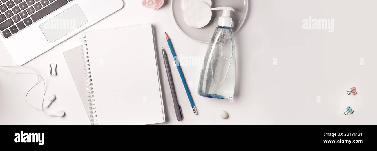 Disposizione piatta con notebook e cancelleria, igienizzatore per mani per ufficio domestico Foto Stock