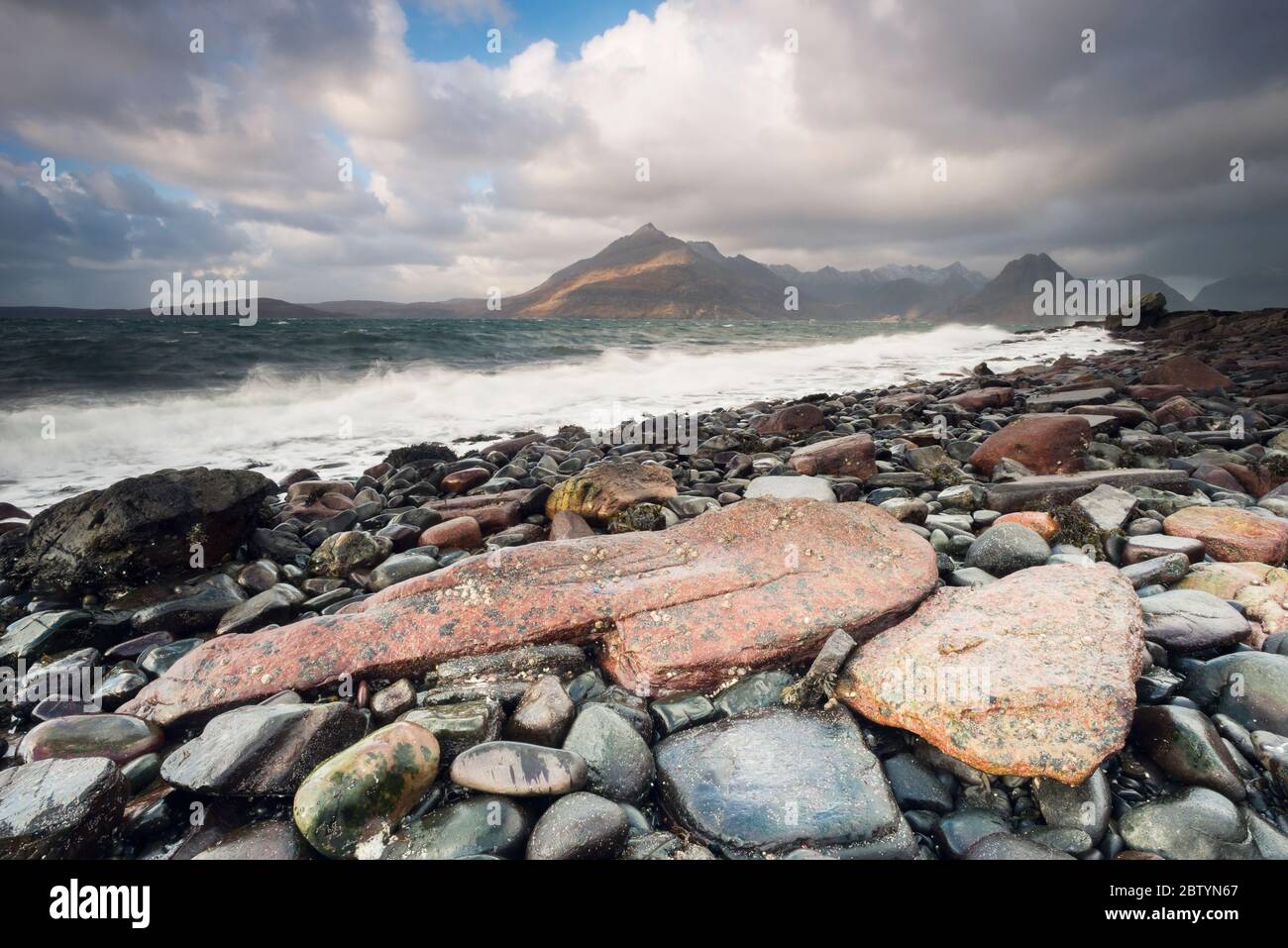 Le onde si infrangono contro rocce e ciottoli sulla baia di Elgol contro lo splendido sfondo dei Black Cullins. Highlands, Isola di Skye, Scozia Foto Stock