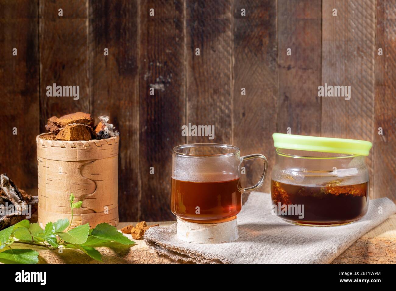 Bevanda curativa da chaga di funghi di betulla, pezzi di funghi, ramoscello su tavola di legno vecchio sfondo di legno. Chaga caffè o tè. Forte antiossidante IR Foto Stock