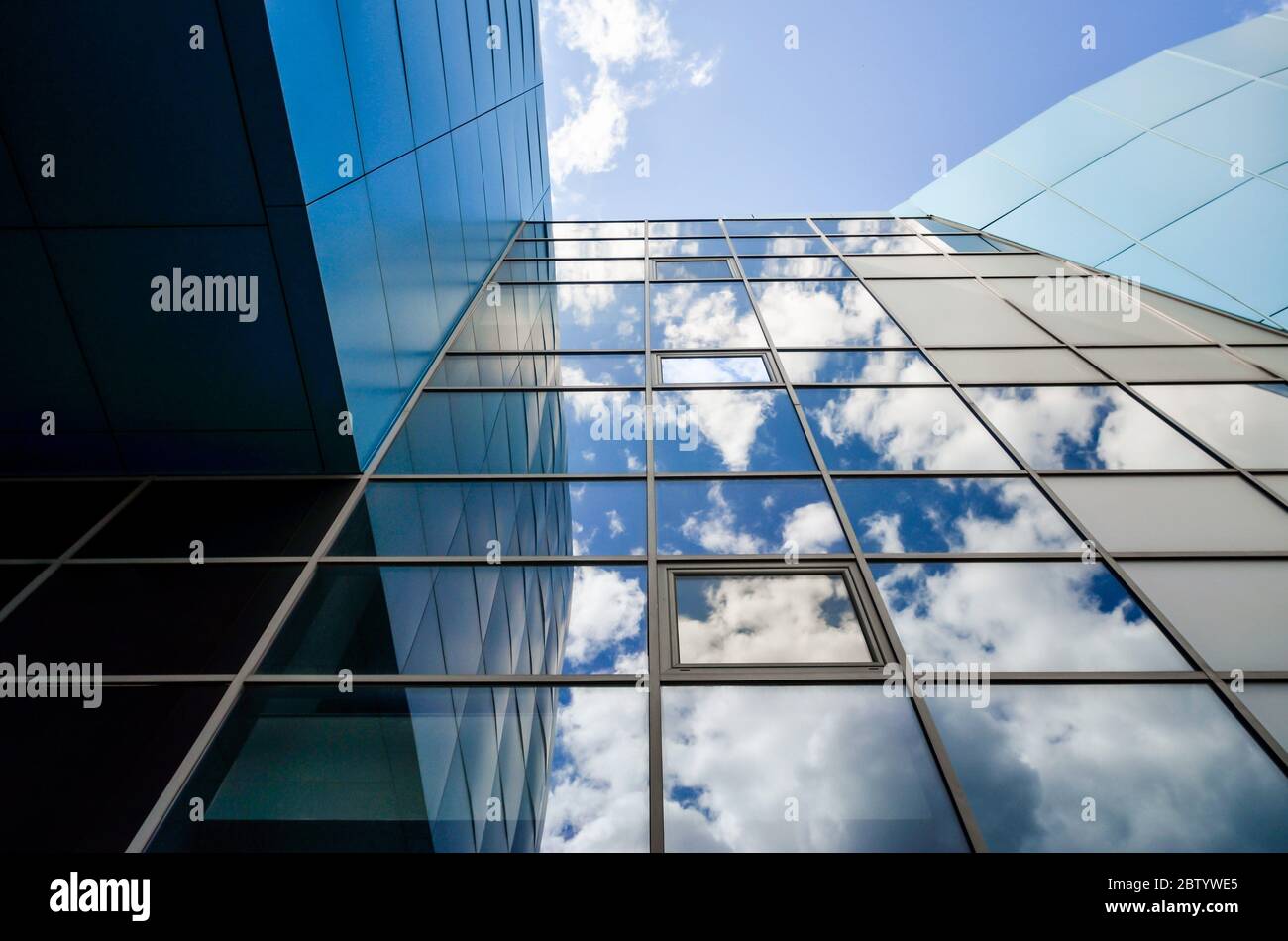 riflesso del cielo blu con le nuvole in una moderna finestra dell'edificio degli uffici Foto Stock