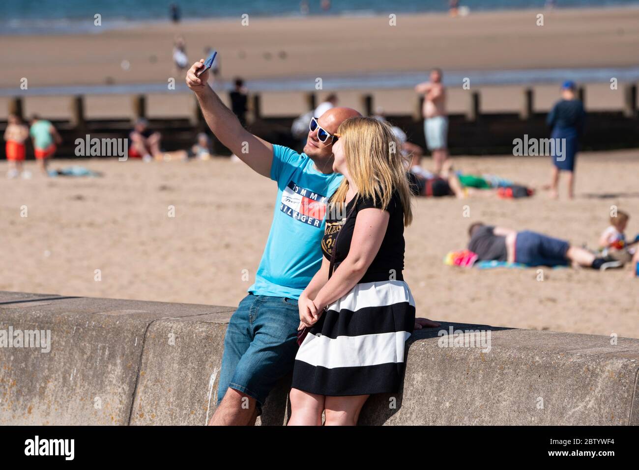 Portobello, Scozia, Regno Unito. 28 maggio 2020. Il caldo clima soleggiato con temperature che raggiungono i 24°C ha portato molte persone alla spiaggia e alla passeggiata a Portobello, Edimburgo. Il pubblico sembra sentire che il blocco è in fase di relax stanno approfittando del bel tempo per prendere il sole e godere dei molti caffè che ora offrono spuntini da asporto. Iain Masterton/Alamy Live News Foto Stock