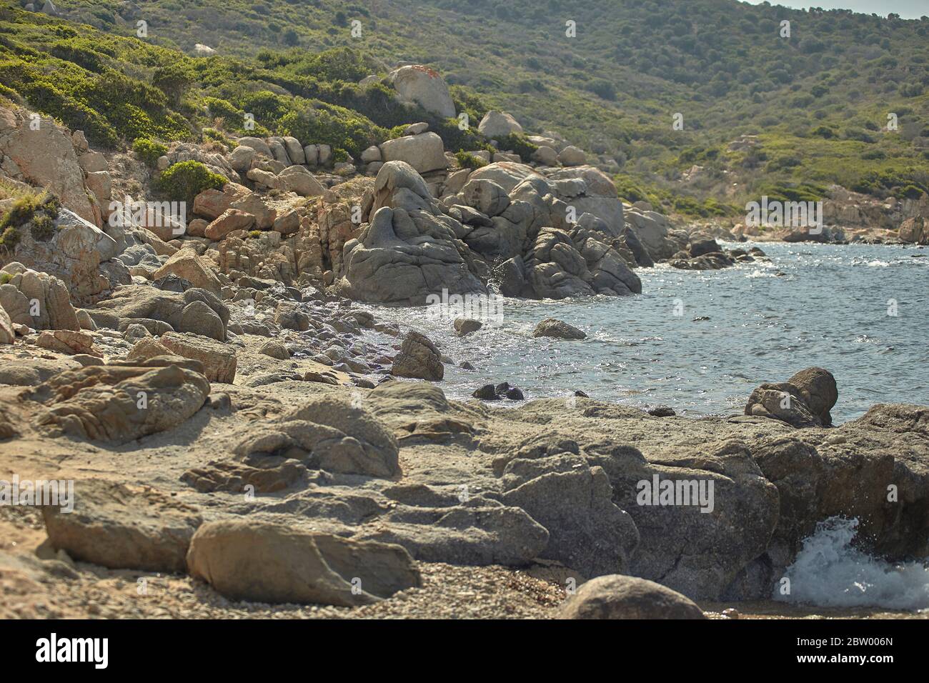 Roccia di una costa mediterranea che si fonde con il mare e la spiaggia sottostante. Foto Stock
