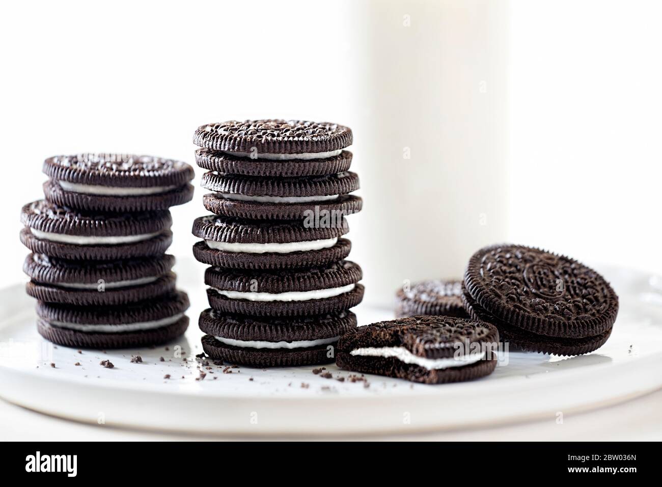 Biscotti Oreo impilati con latte su sfondo bianco Foto Stock